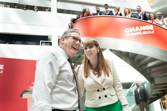 Sir Keir Starmer and deputy Labour leader Angela Rayner watched by Labour supporters standing on a spiral staircase