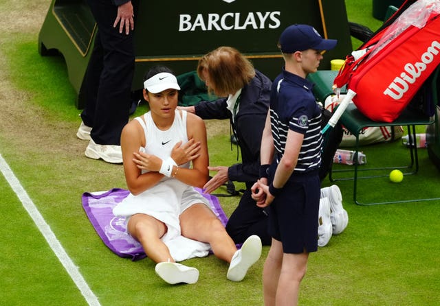 Emma Raducanu sits on the floor as she receives treatment for an injury