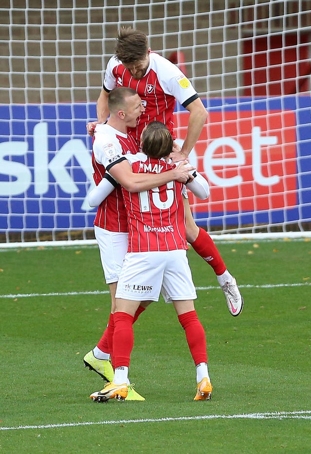 Cheltenham's Will Boyle (centre) with Alfie May (bottom) and Charlie Raglan (top) celebrate taking the lead against Premier League Manchester City Bet League Two – Jonny-Rocks Stadium