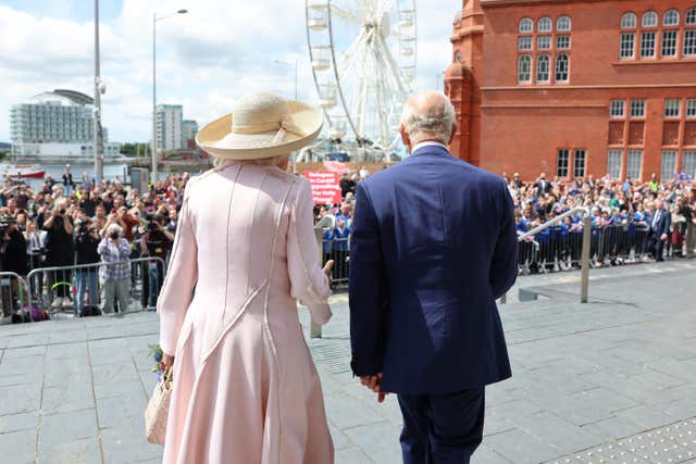 The King and Queen walk away from the camera after their visit