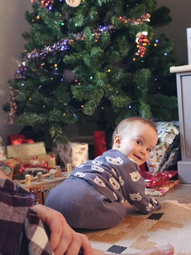 Arthur Ransom sitting on the floor near a Christmas tree