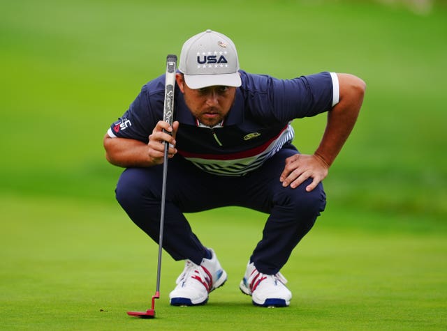 Xander Schauffele bends down to read a putt