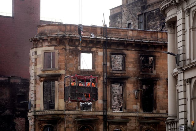 Workmen in a high basket inspect the shell of a fire-damaged building