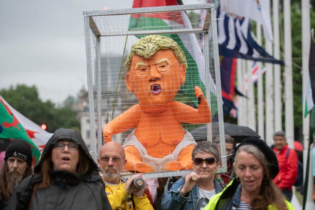 A baby blimp effigy of Donald Trump in a cage