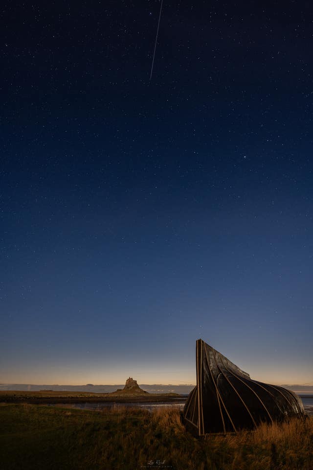 Wide shot of the night skies over Lindisfarne in Northumberland of the Geminid meteor shower