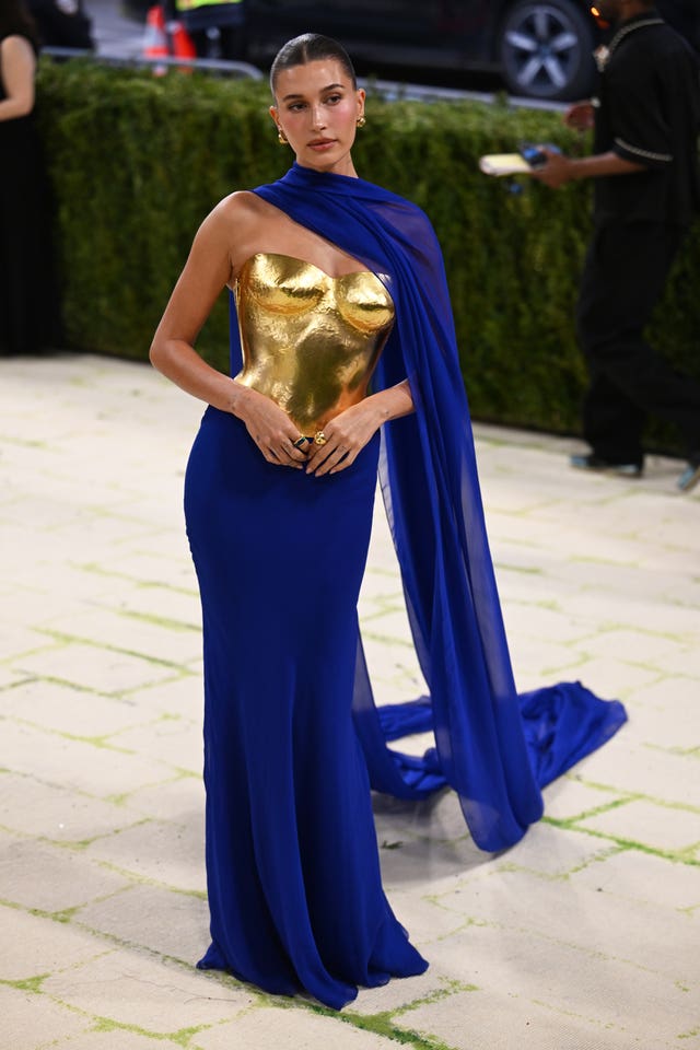 Hailey Bieber posing on the 2026 Met Gala carpet wearing a dress with a gold bodice and blue skirt 