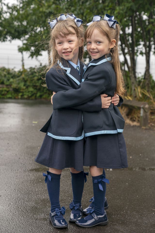 Ellie and Hannah hug and smile in their school uniforms