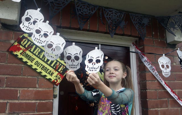 Talulah arranges skull decorations near her front door (Danny Lawson/PA)