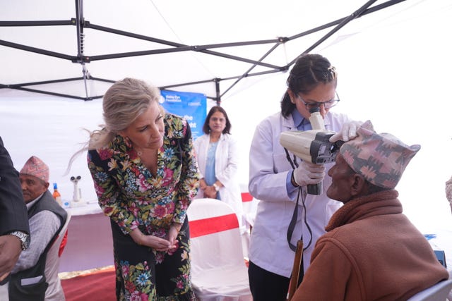 The Duchess of Edinburgh (left) watches a patient receive an eye test during a visit to a hospital