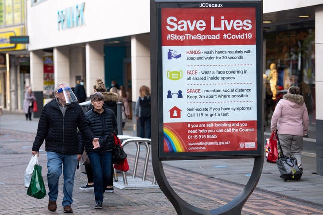 A man wearing a face shield walks past a coronavirus advice sign in Nottingham city centre (Jacob King/PA)