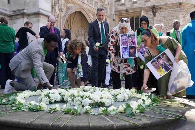 People place white roses in memory of the victims at the Grenfell fire memorial service at Westminster Abbey in London