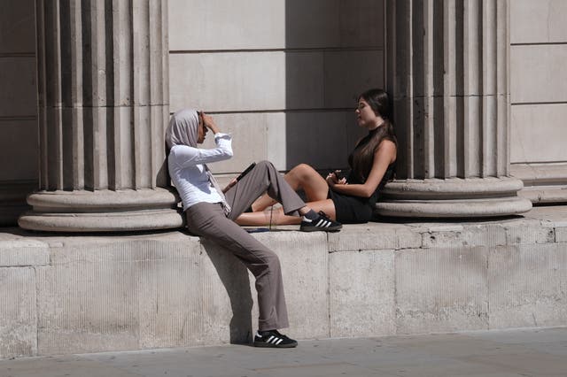 Two women by a building in the sun