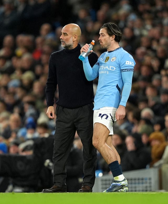 Pep Guardiola talks to substitute Jack Grealish on the touchline during a Manchester City game