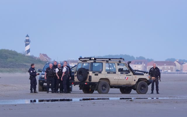 French police officers stand around a vehicle on the beach at Gravelines on Saturday