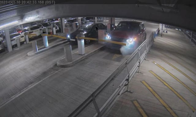 A red Range Rover Sport arriving at a ticket barrier with smoke coming from bonnet