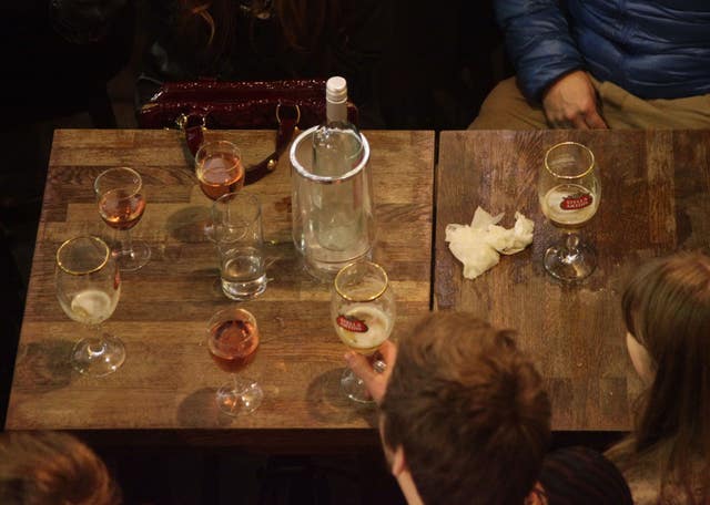 People sat around a table drinking wine and lager in a pub