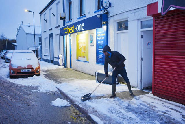 A man clears snow from a pavement in Dowlais, south Wales 