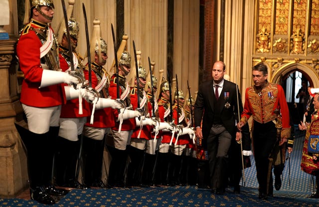 The Duke of Cambridge walks past the Household Cavalry in the Norman Porch at the Palace of Westminster ahead of the State Opening of Parliament in the House of Lords, London