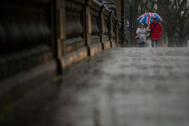 People shield themselves from heavy rain as they walk in Worcester (Jacob King/PA)