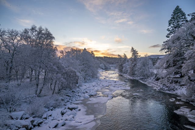 The sun rises over a partially frozen river