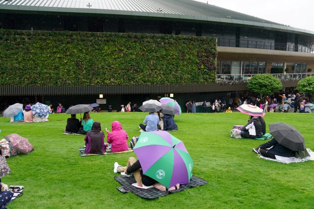 Fans shelter under umbrellas on 'Murray Mound'