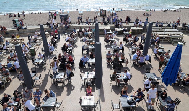 Customers enjoy the sunshine in a bar on the promenade in Brighton 