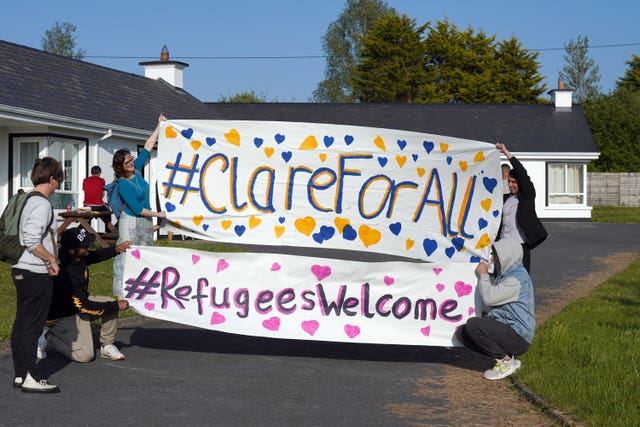 Local residents with asylum seekers hold up a banner supporting refugees
