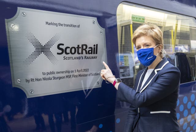 Nicola Sturgeon pointing to a plaque on a ScotRail train