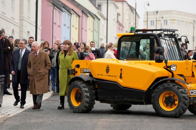 The King, PM and Deputy PM walk past a Duchy of Cornwall tractor as they visit the next building phase of the Nansledan development