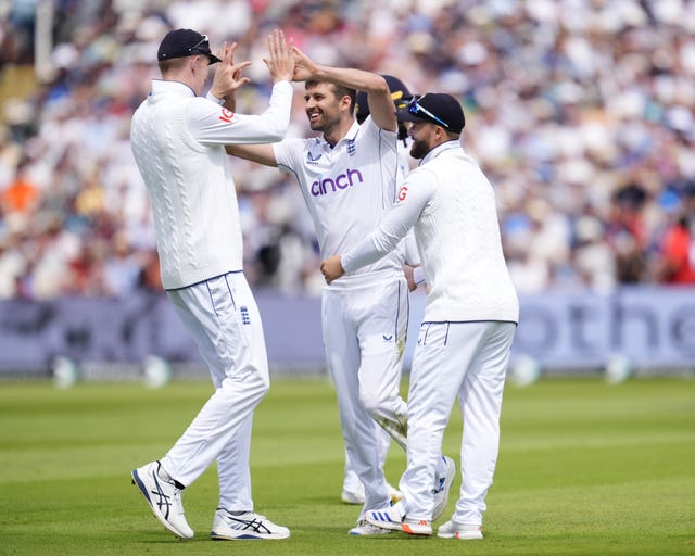 England’s Mark Wood (centre) celebrates with Zak Crawley (left) and Ben Duckett after dismissing Kirk McKenzie (Nick Potts/PA)