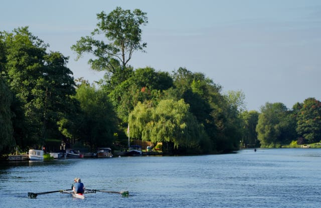 Early-morning rowers travel along the River Thames, 