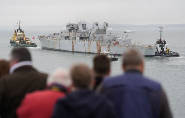 People watching from the shore as HMS Bristol is towed away