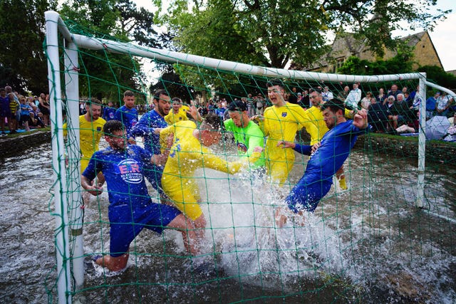 Footballers from Bourton Rovers create a splash as they fight for the ball during the annual River Windrush football match, which has been taking place for more than 100 years in the Cotswolds village of Bourton-in-the-Water, Gloucestershire (Ben Birchall/PA)