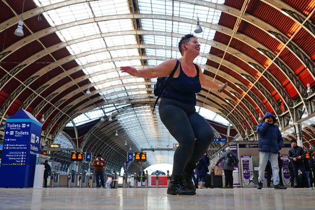 A passenger waiting for a train, who said she had nothing else to do, dancing in Paddington station in London, where trains have been cancelled due to Storm Eunice 