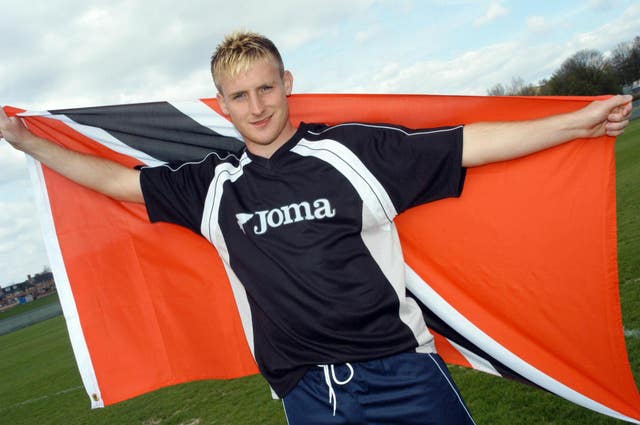 Chris Birchall poses with a flag of the Trinidad and Tobago