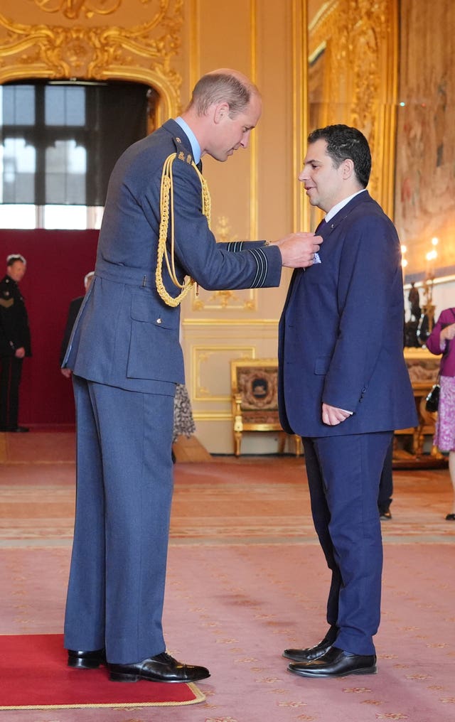 The Prince of Wales pins an MBE medal on Justin Cohen inside Windsor Castle