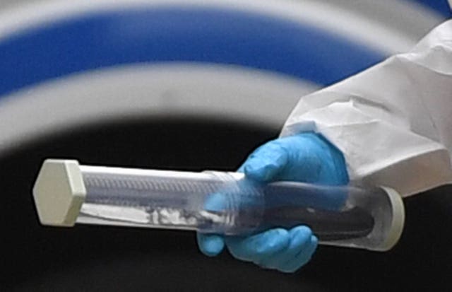 A police forensics officer holding a sealed container with a black handled knife inside, in Edmund Street in Birmingham (Jacob King/PA)