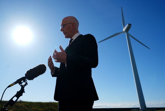 John Swinney speaking in front of a wind turbine