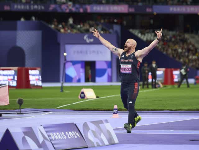 Dan Pembroke raises his arms as he celebrates winning gold with a world record throw 