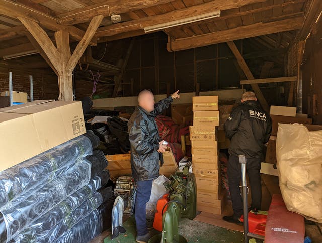 Two unidentified law enforcement officers searching a storage building.