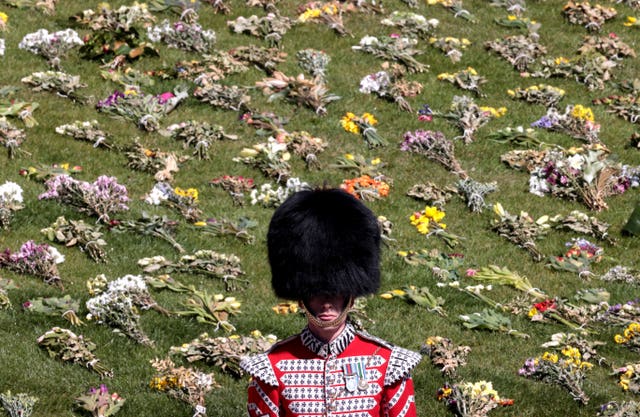 A guard stands in front of flowers laid out on the grass outside St George’s Chapel, Windsor Castle, Berkshire, ahead of the funeral of the Duke of Edinburgh