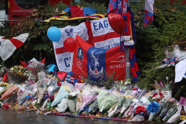 Floral tributes and Crystal Palace football colours left near the scene where a tram crashed, killing seven people, in Croydon, south London (Steve Parsons/PA)