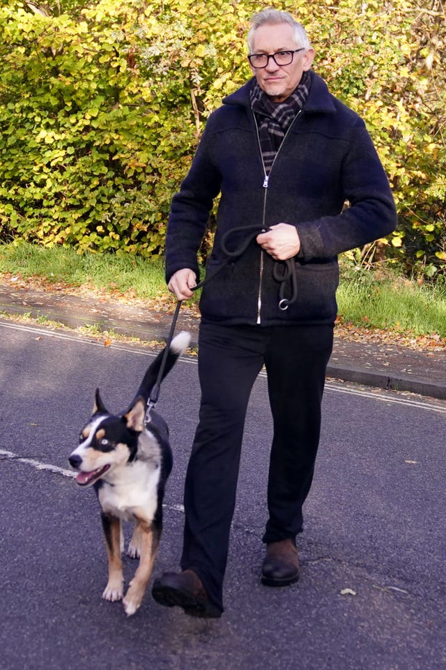 Gary Lineker wearing a coat and walking his dog