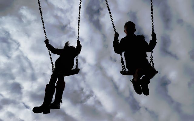 Silhouettes of children playing on swins