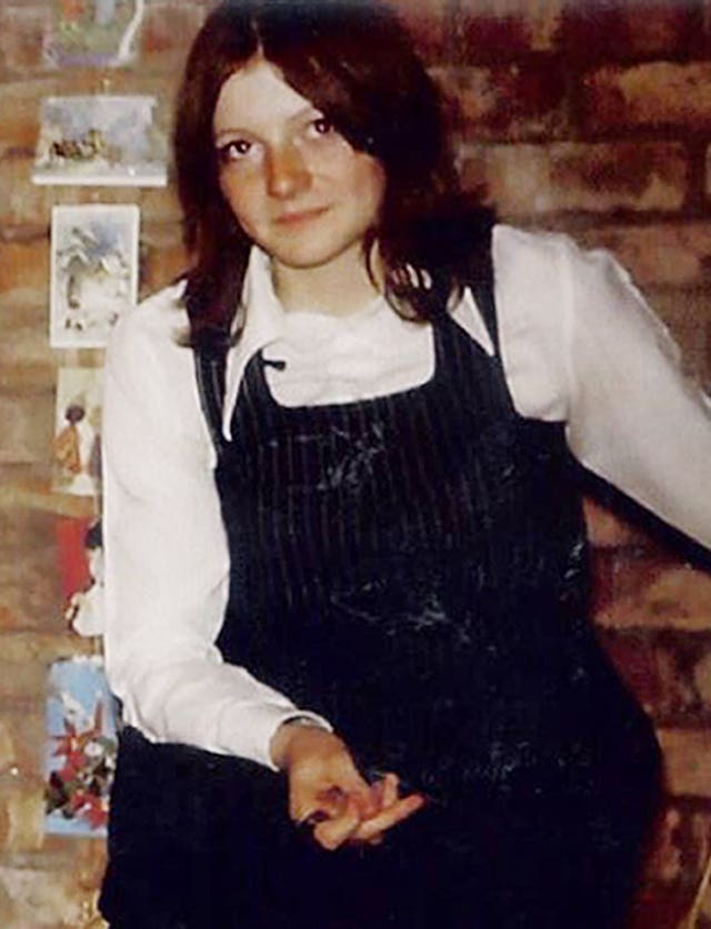 A young woman with dark hair wearing a white shirt and dark, sleeveless jumper