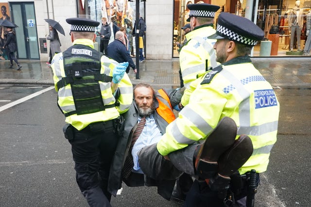 Police officers deal with activists from Just Stop Oil during their protest outside Harrods department store in Knightbridge, London on Thursday October 20, 2022