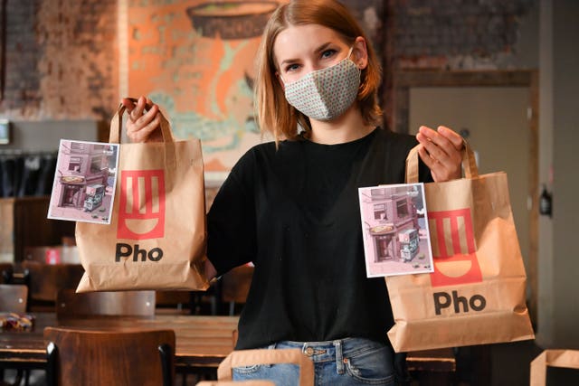 Staff member holds lunch bags at Pho