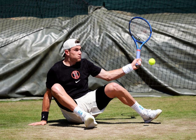 Jack Draper hits a shot while sitting on the floor during a practice session