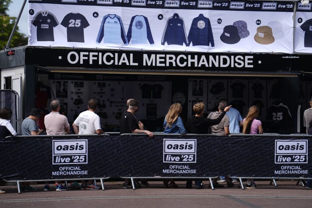 Oasis fans stand in the queue for the official merchandise stand outside the Principality Stadium in Cardiff