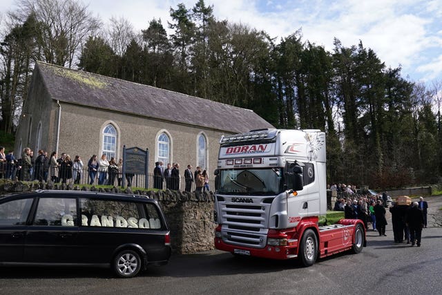 The coffin of Keith Morrison is taken from the back of a truck 